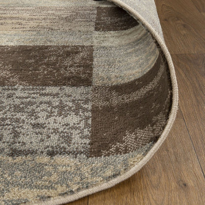 Rectangular area rug in earthy brown and beige patchwork, textured weave, rolled edge on wooden floor.