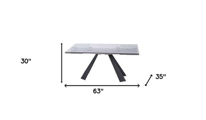 Clear glass dining table with black angled metal legs in a modern A-frame design; 63" long, 30" high, 35" deep