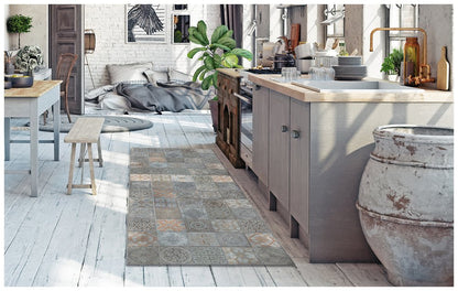 Bright modern kitchen with a light wood island, gray cabinets, and patterned tile rug runner, stools and a potted plant.