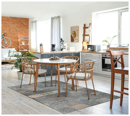 Bright open-plan kitchen and dining area with round white table, rattan chairs, brick accent wall, turquoise bike decor, and potted plants.