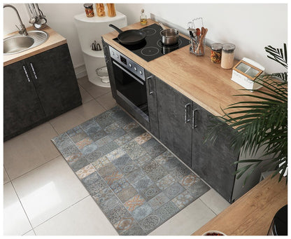 Modern kitchen with dark cabinet units, wooden countertop, stainless sink and oven, and blue-grey patchwork tile rug in front.