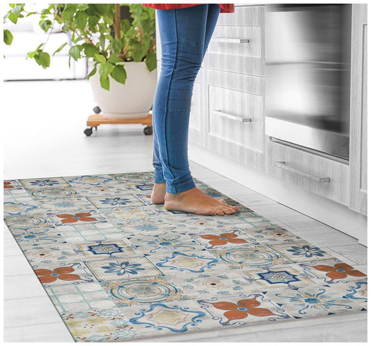 Barefoot person in blue jeans stands on a colorful patterned rug in a modern kitchen.