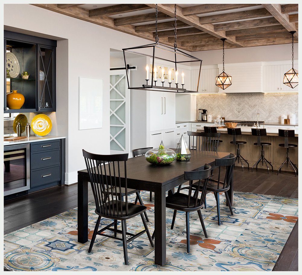Dark wood rectangular dining table with black Windsor chairs in a modern kitchen-dining space; geometric pendant lights.