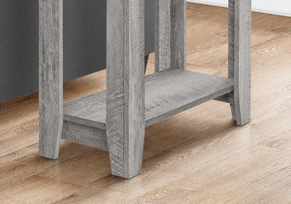 Greywashed wooden end table with lower shelf and square legs on light hardwood floor.