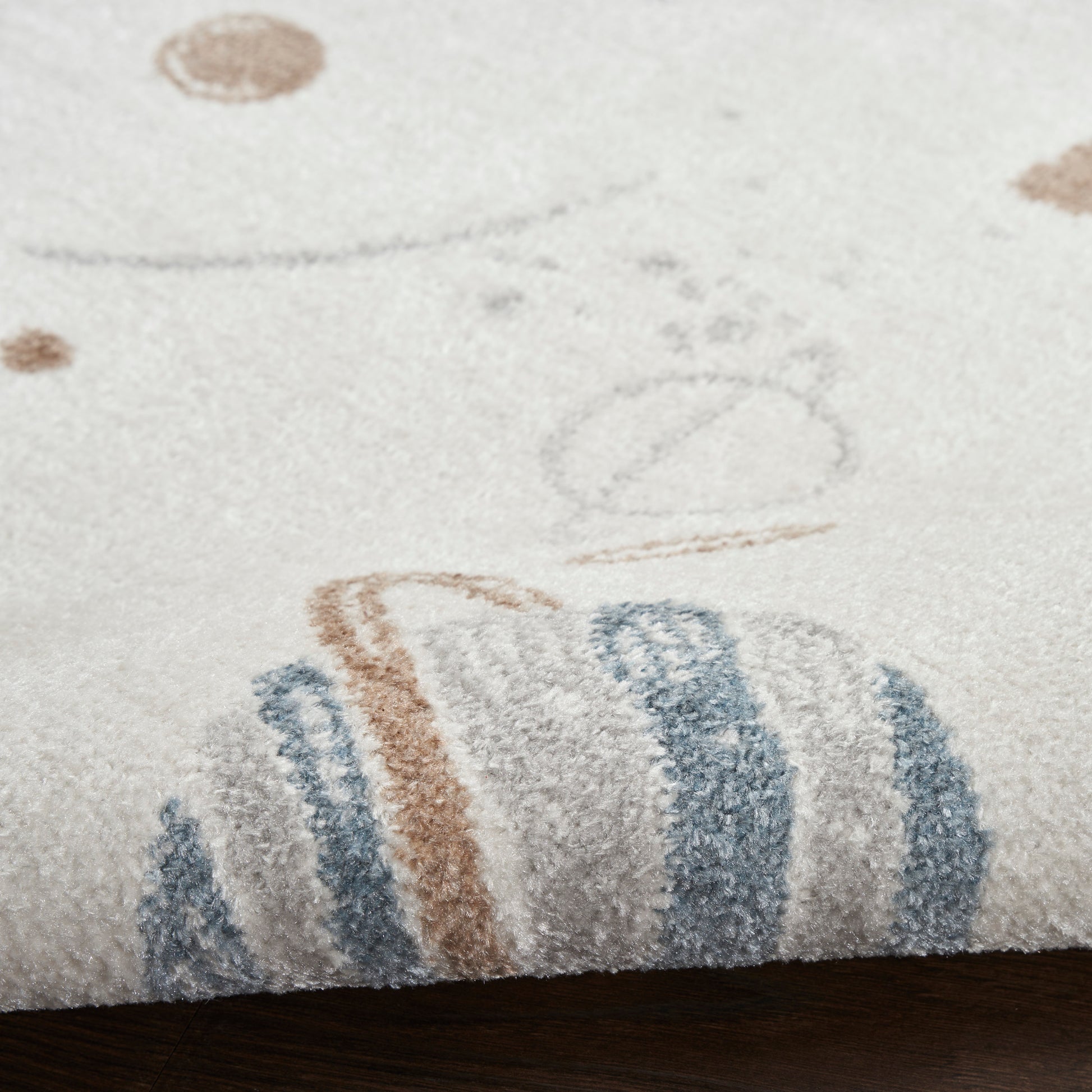 Cream shag rug with soft pile, blue and brown striped edge and playful circular motifs; ideal for kids’ rooms.
