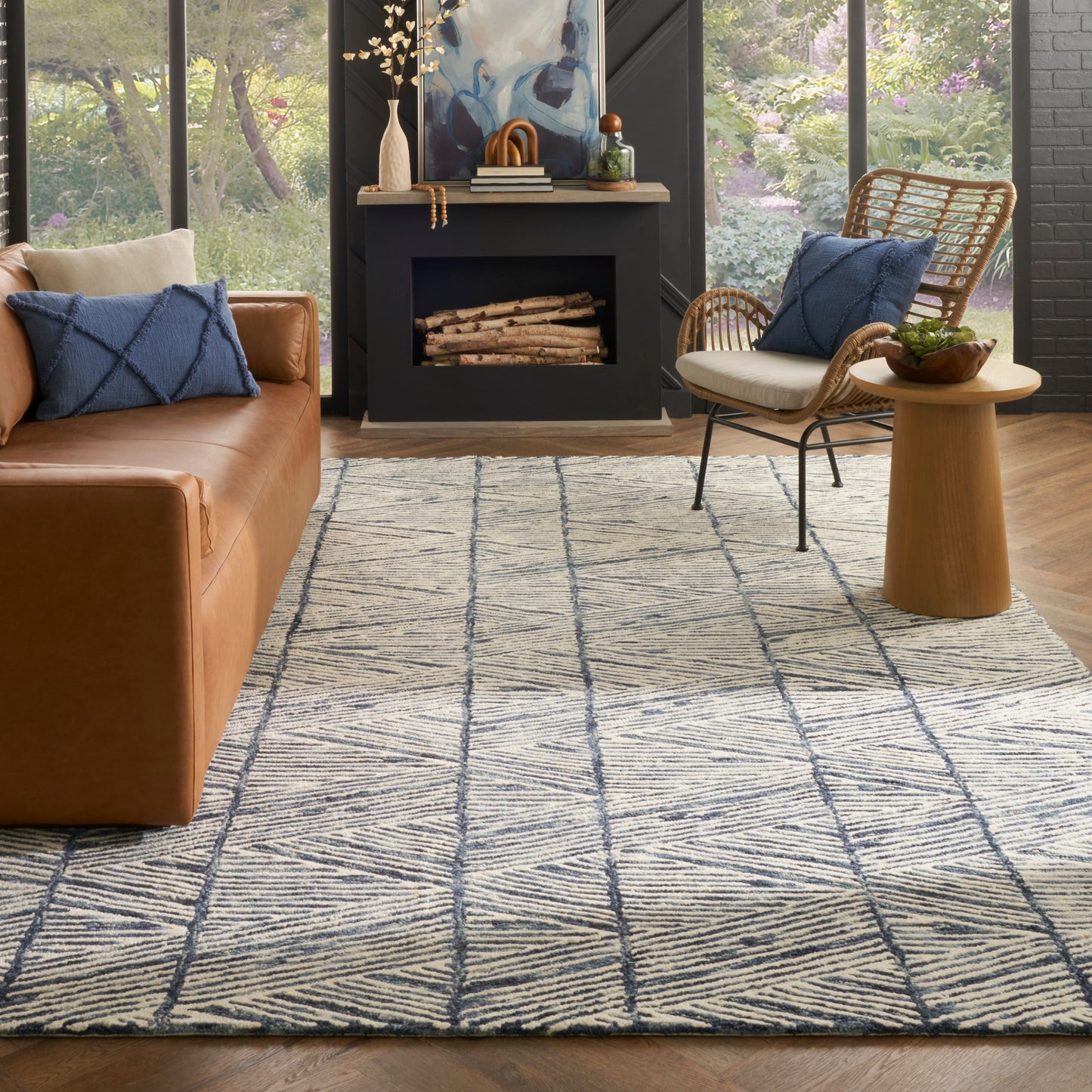 Ivory and navy geometric area rug on wood floor, paired with brown leather sofa and wicker lounge chair.