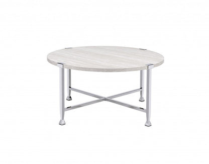 Round metal coffee table with a white and silver finish and cross-braced legs.