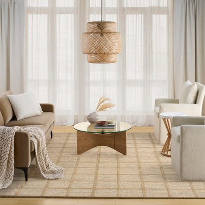 Boho-modern living room with beige sofa, cream chairs, woven rattan pendant light, round glass coffee table, and a rug.
