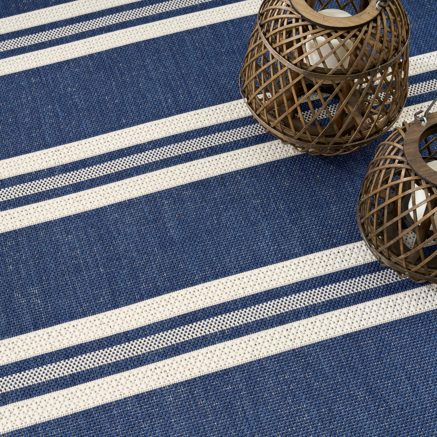 Blue and white striped woven rug with round brown wicker lanterns and white candles.