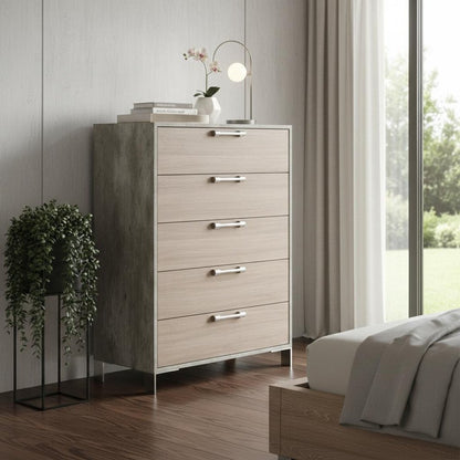 Light wood five-drawer dresser with slender metal legs & chrome handles in a modern bedroom, lamp & plant on top.