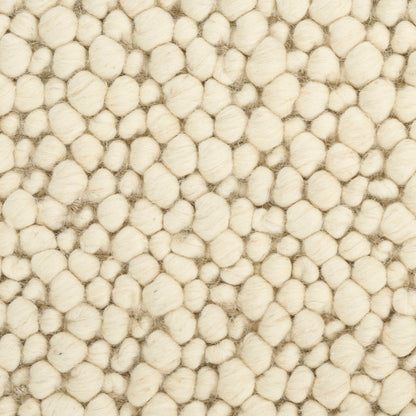 Cream boucle rug with dense, rounded wool tufts creating a soft, cozy textured surface.