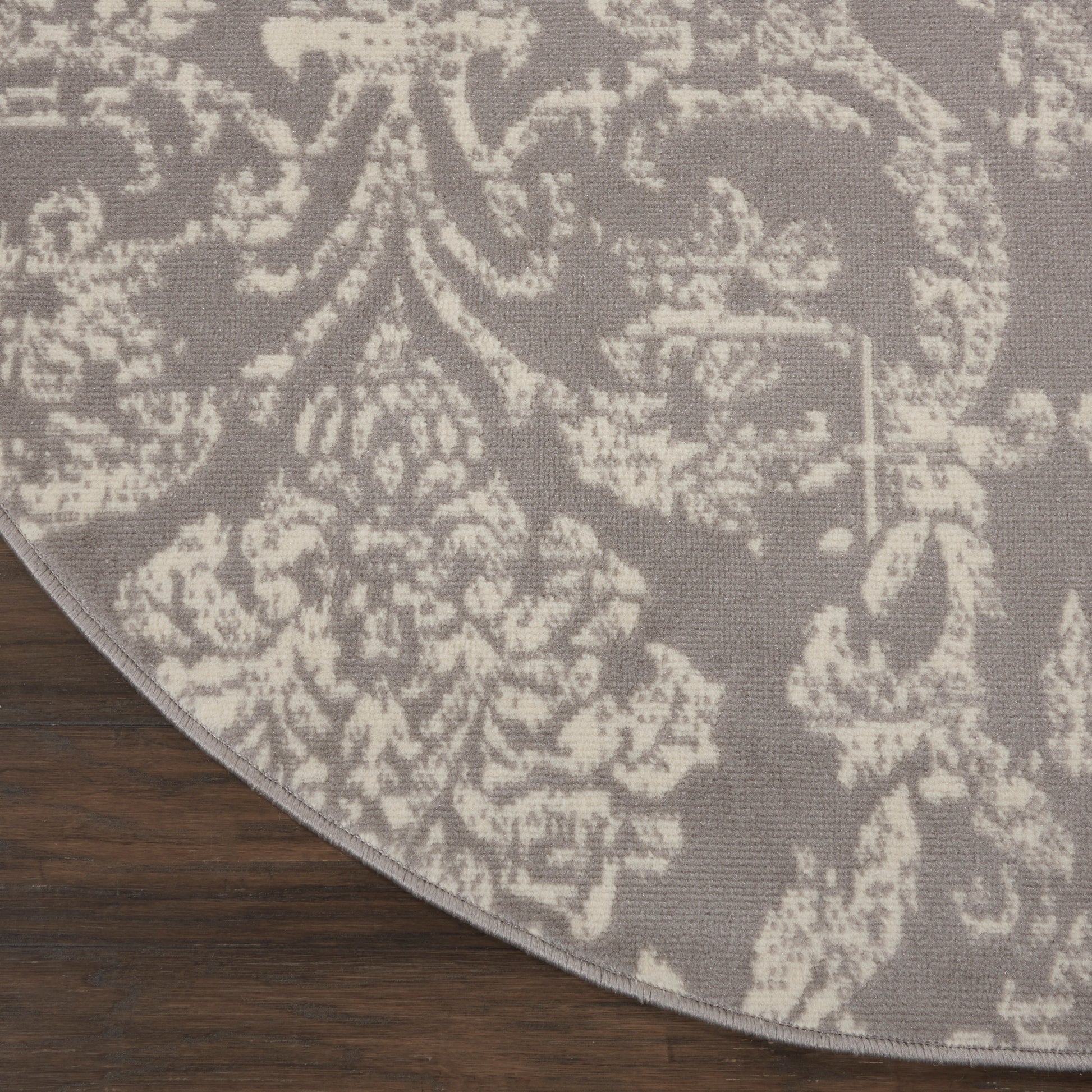 Round 8' diameter gray rug with cream damask pattern and light edge on dark wood floor