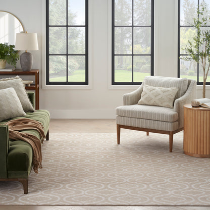 Bright living room with black-framed windows, beige patterned rug, green sofa with a throw, and a cream striped armchair.
