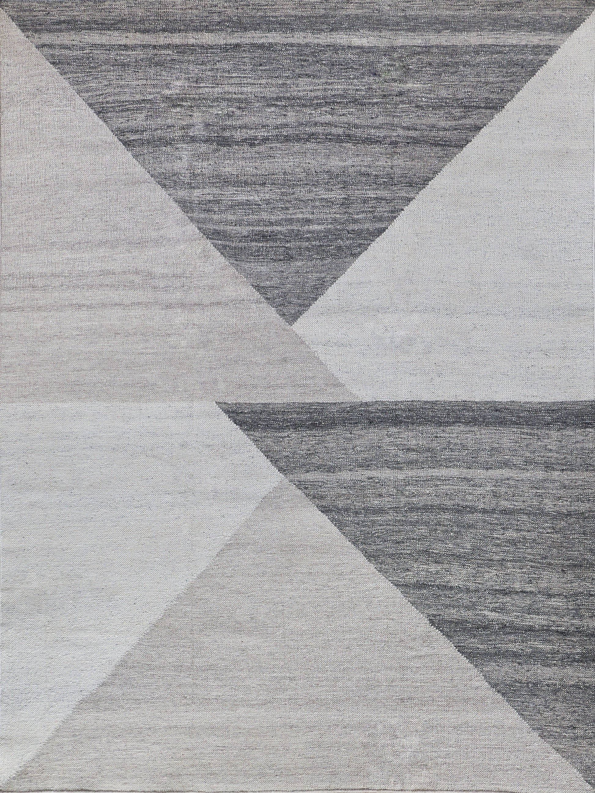 Geometric area rug with overlapping triangles in charcoal, dark grey, light grey, and beige.