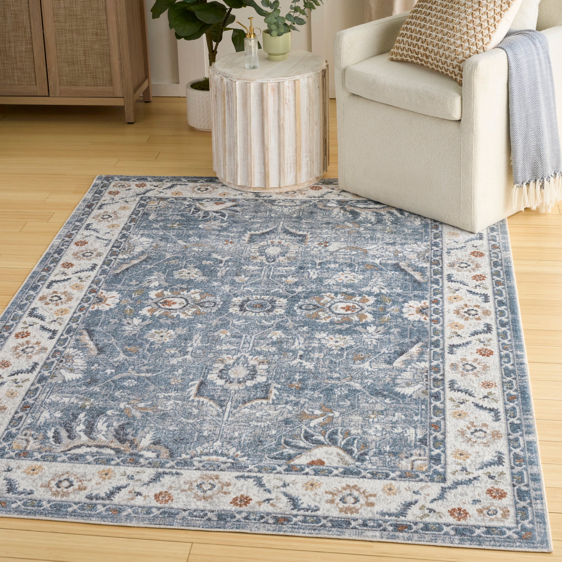 Blue oriental-style area rug with ivory border & floral medallions in a cozy living room.