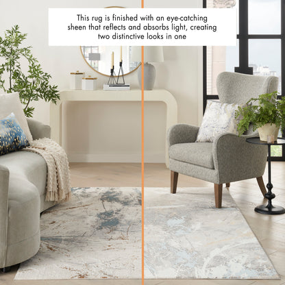 Modern living room with abstract grey-blue rug, light gray sofa and armchair, plants, round mirror above a console.
