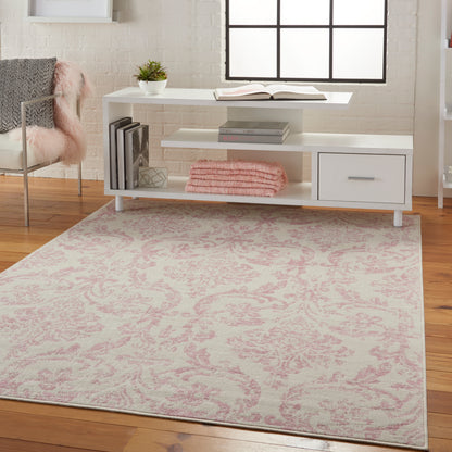 Rectangular cream area rug with pink damask pattern on a wooden floor.