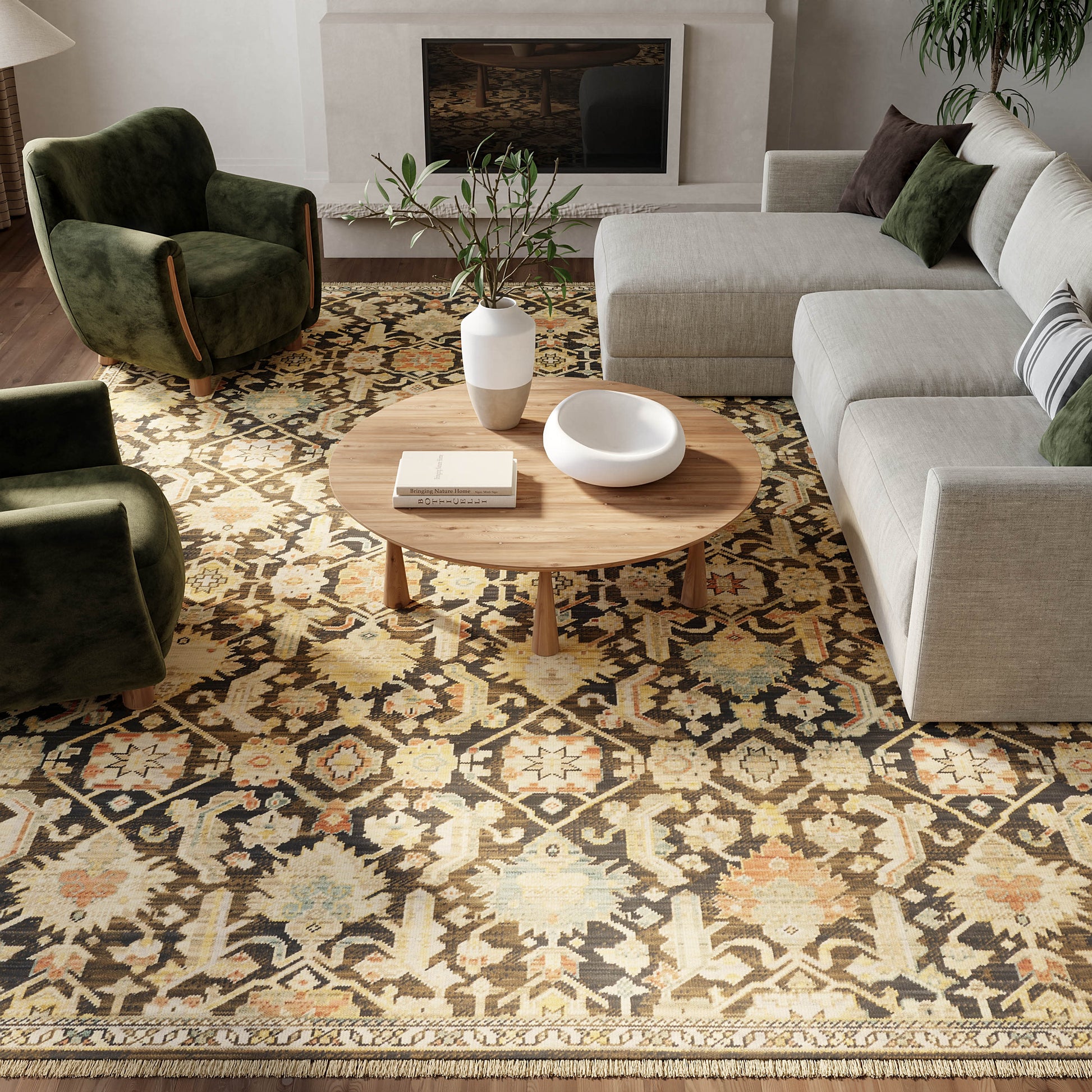 Living room with round wooden coffee table on a patterned rug, beige sectional, dark green velvet armchairs, white vase.