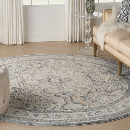 Round area rug with intricate gray-blue medallion pattern on light wood floor in a cozy living room.