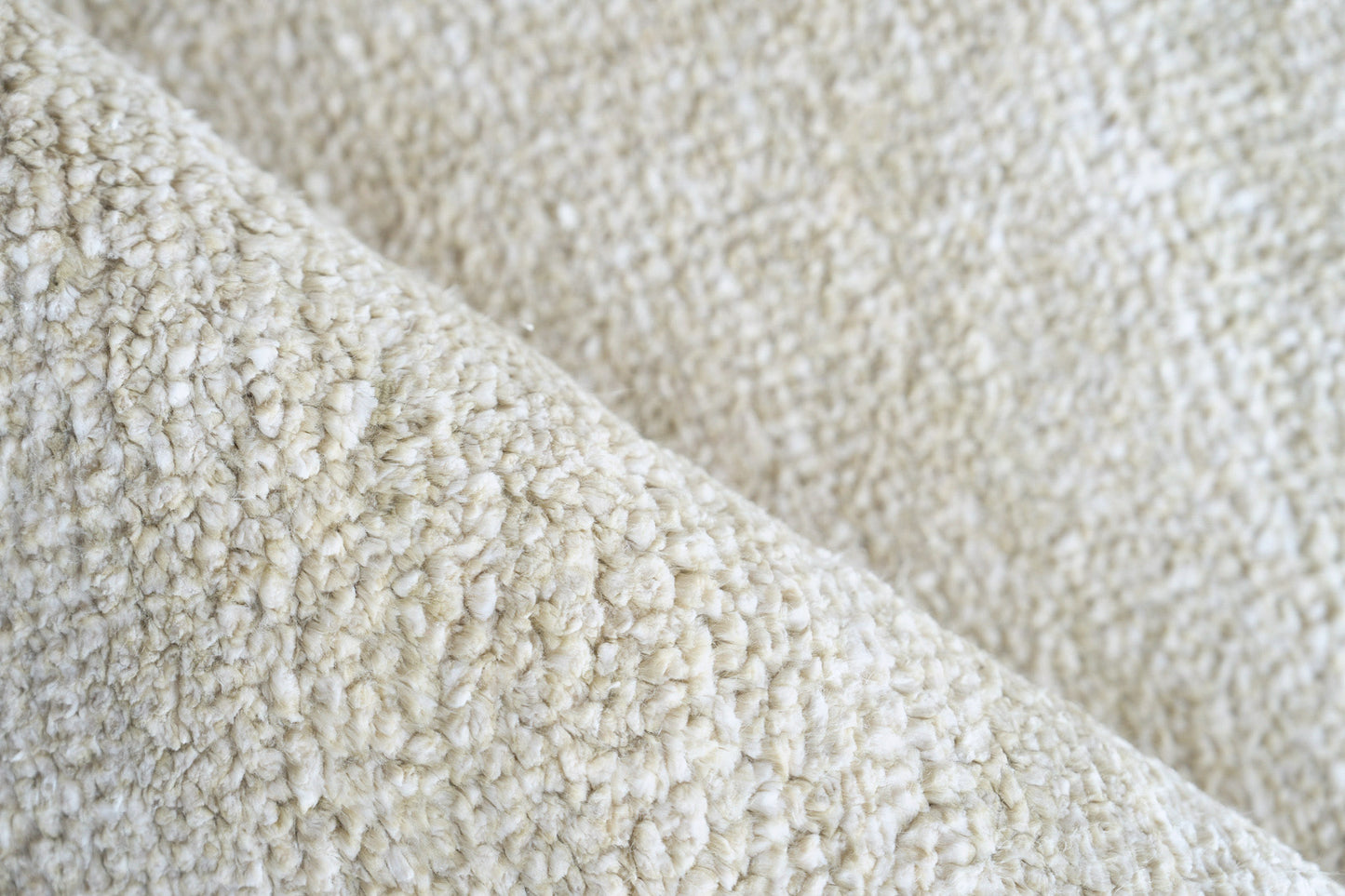 Cream plush pile close-up with boucle texture on an indoor hand-knotted rug.