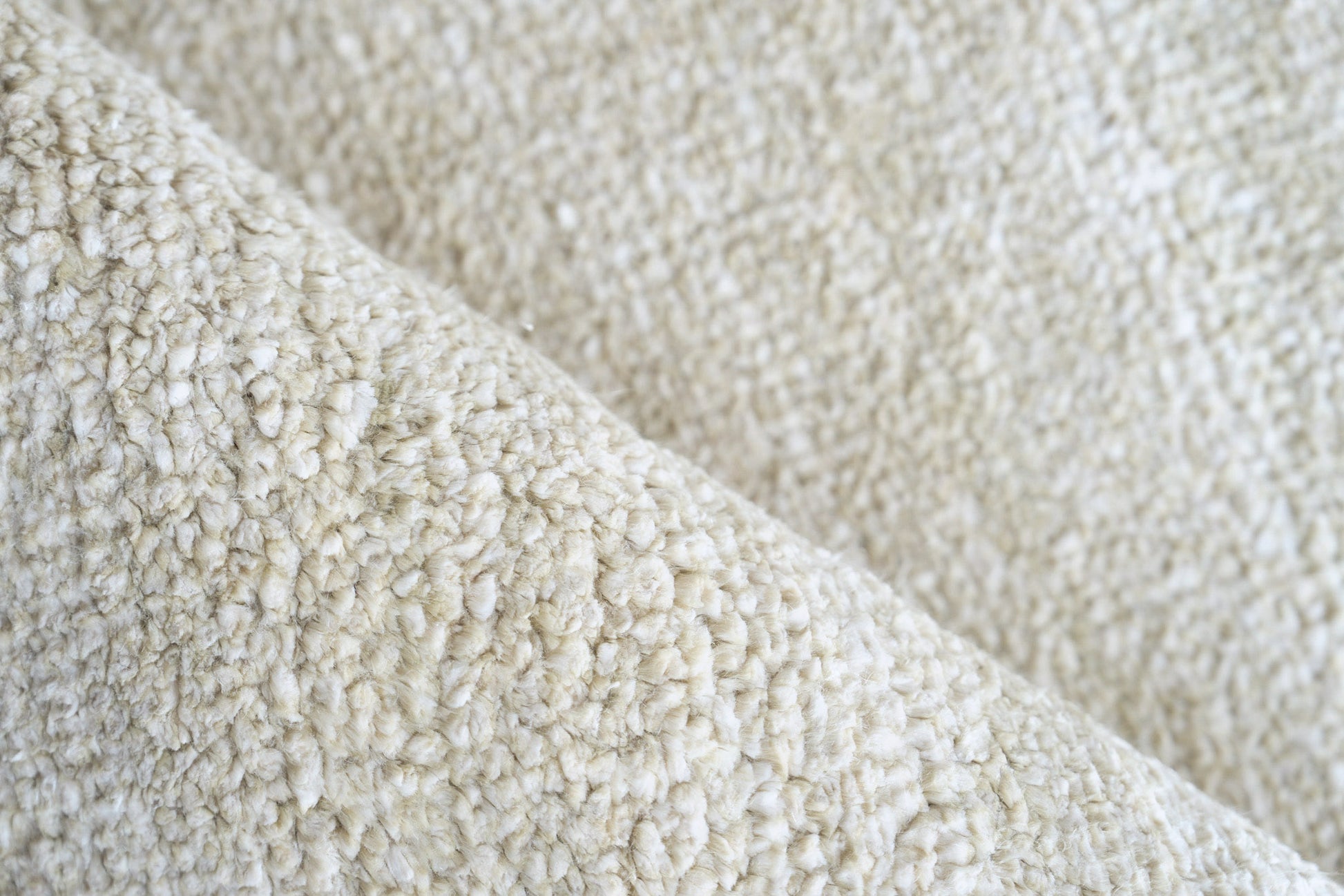 Cream plush pile close-up with boucle texture on an indoor hand-knotted rug.