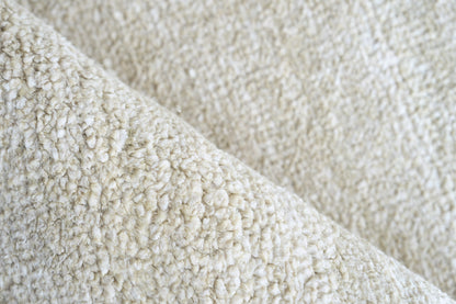 Cream plush pile close-up with boucle texture on an indoor hand-knotted rug.