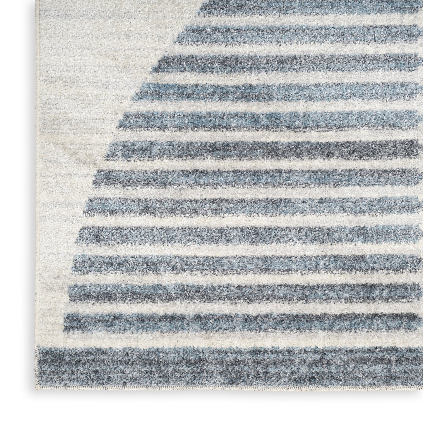 Close-up of a soft area rug with light cream base and navy curved stripes, woven texture.