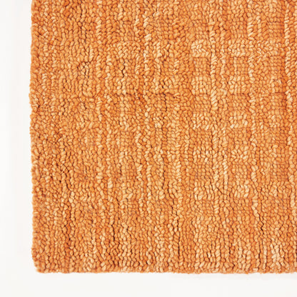 Close-up of orange loop-pile runner rug with chunky texture and warm terracotta tones.