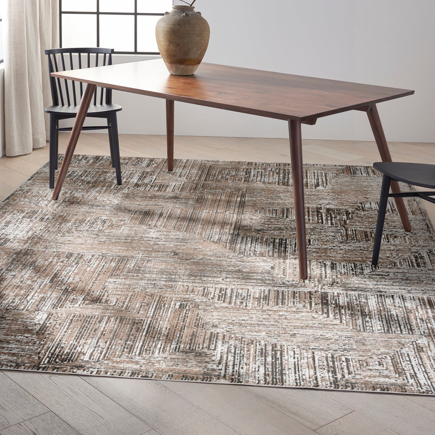 Mid-century walnut dining table with tapered legs, black chairs, ceramic vase centerpiece on a textured geometric rug.