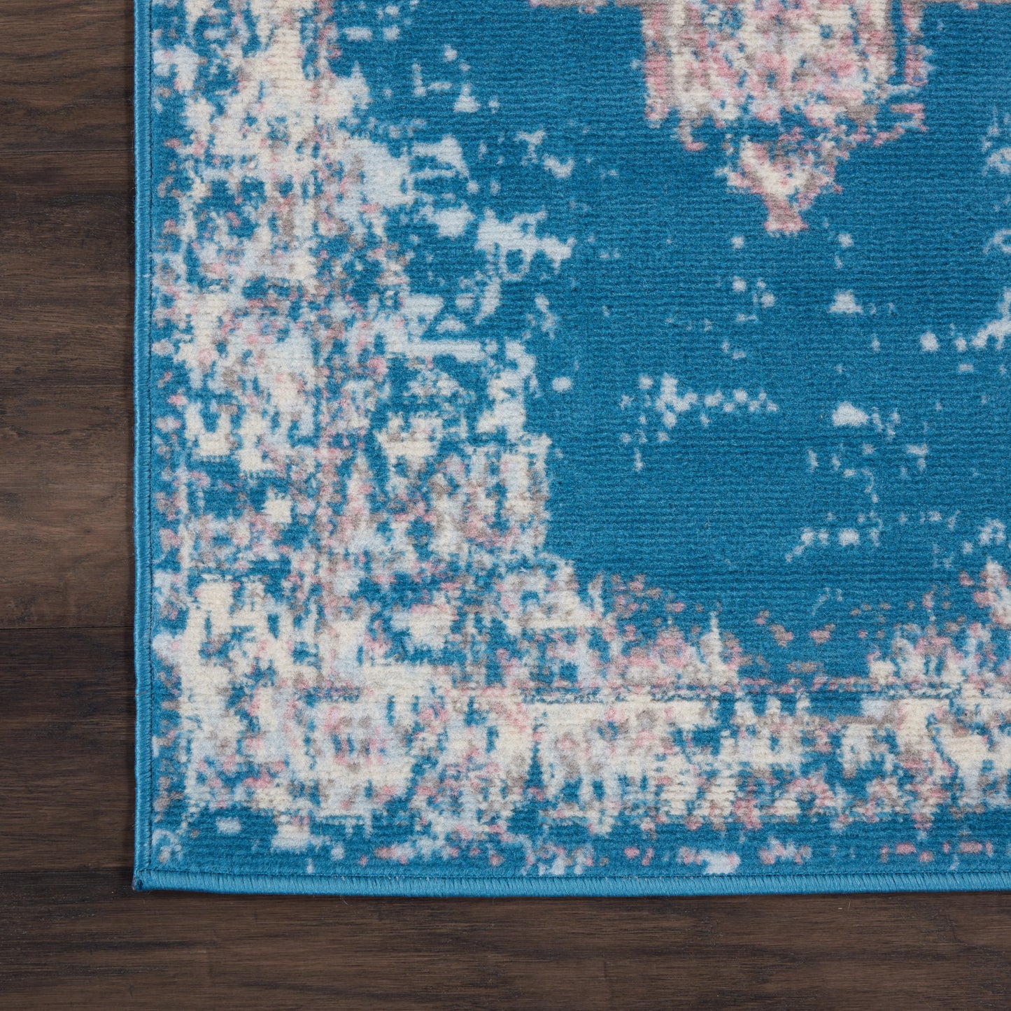 Teal blue distressed runner rug with pink and cream pattern, teal border, on dark wood floor