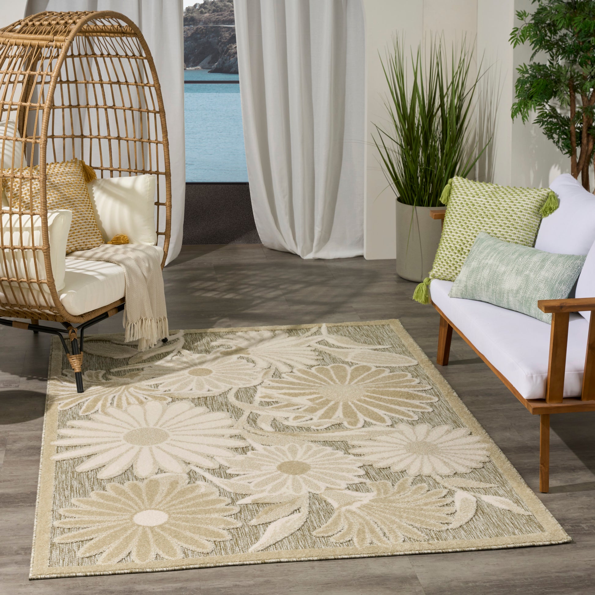 Beige floral area rug with large daisy motifs; wicker egg chair, white cushions, & potted greenery in a living room.