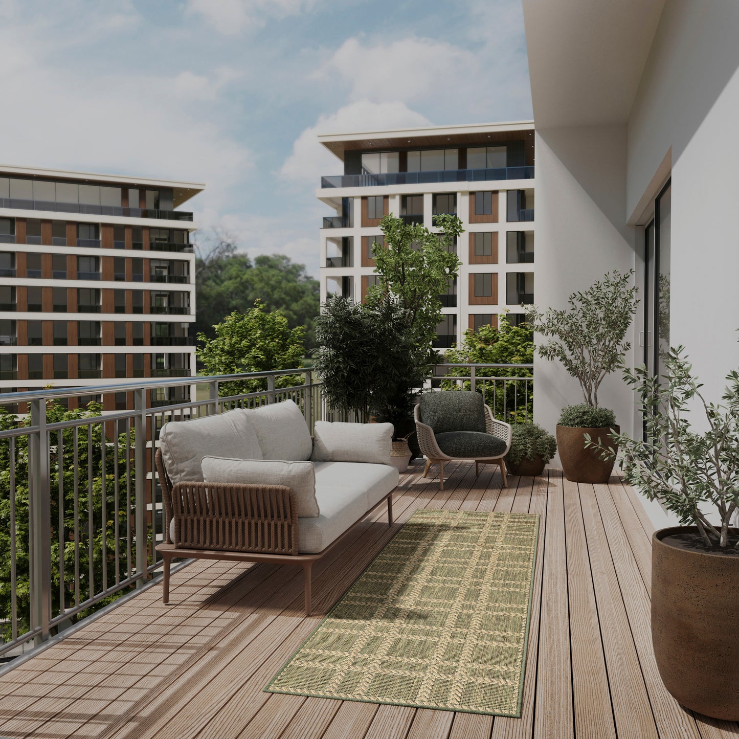 Modern balcony with woven rattan sofa and armchairs, beige cushions, green patterned rug, potted trees, wooden decking.