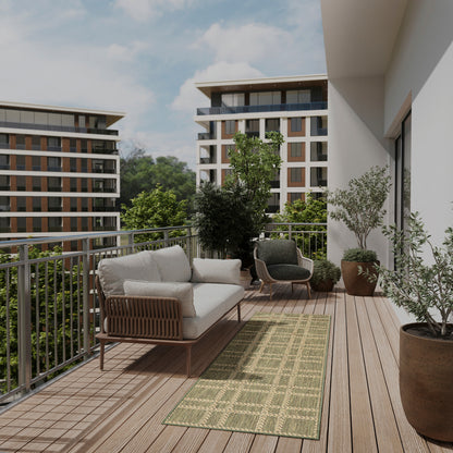 Modern balcony with woven rattan sofa and armchairs, beige cushions, green patterned rug, potted trees, wooden decking.