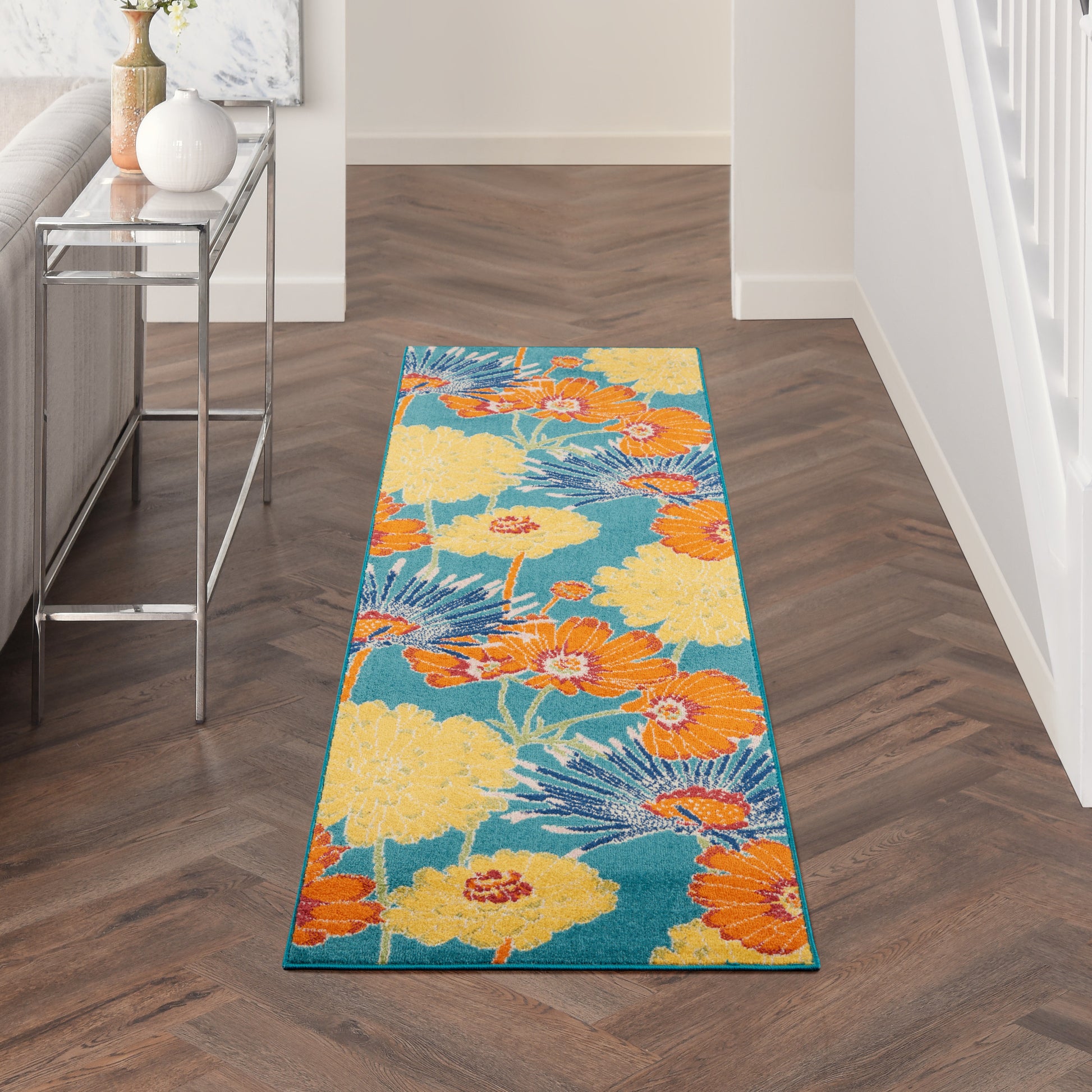 Long hallway runner rug with teal background and large yellow and orange tropical flowers; modern floral print.
