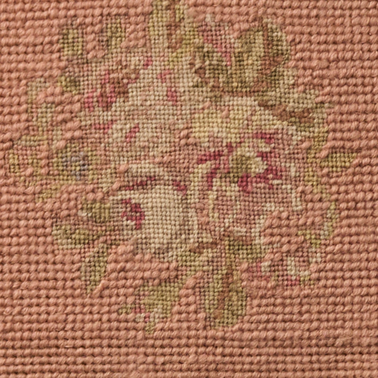Close-up of pink woven fabric with a cream and green floral bouquet pattern; tapestry-style textile.
