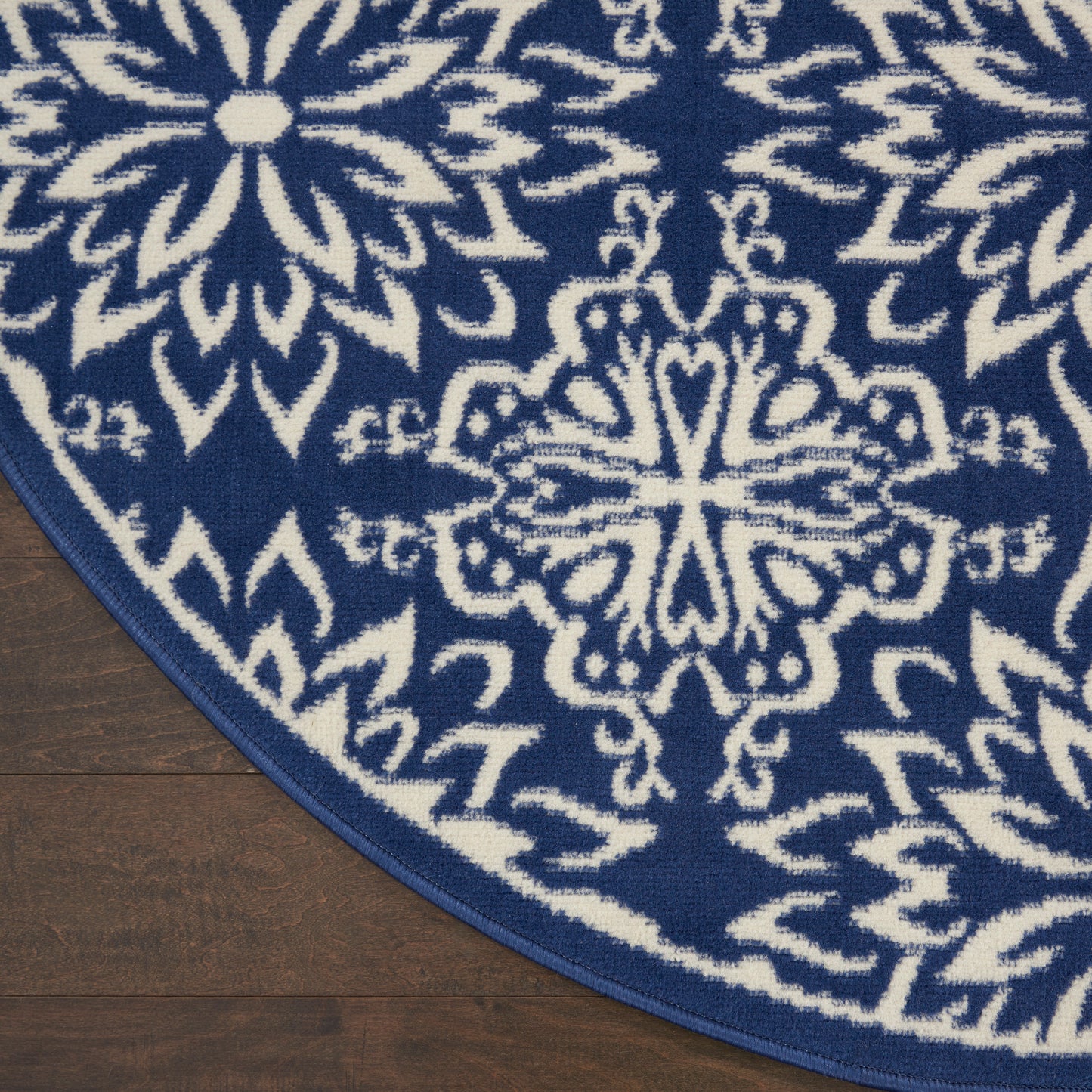 Round navy rug with white mandala and snowflake motifs on wooden floor.
