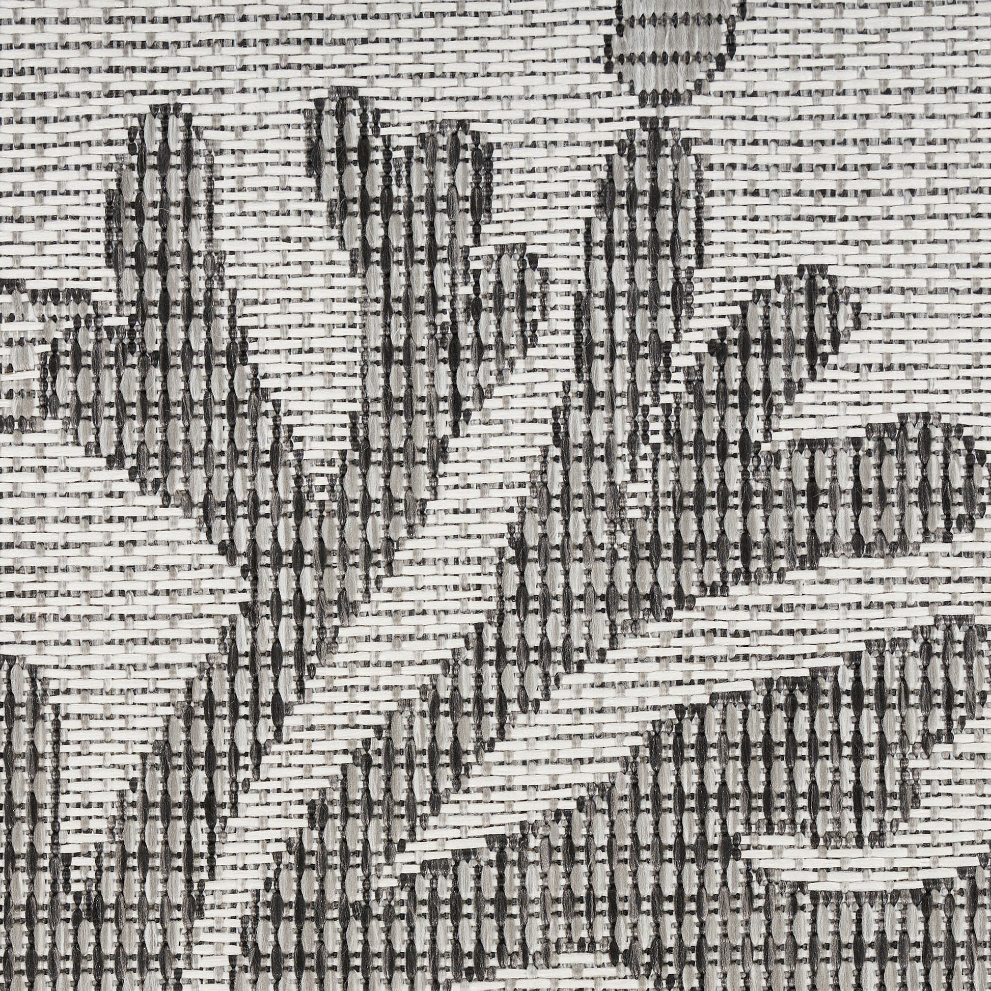 Woven rug with charcoal leaf motifs on a natural beige background; textured, rustic textile.