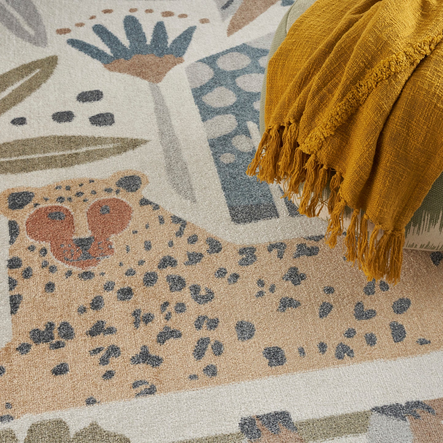 Beige abstract area rug with blue, teal & orange shapes; mustard yellow fringed throw draped along edge.