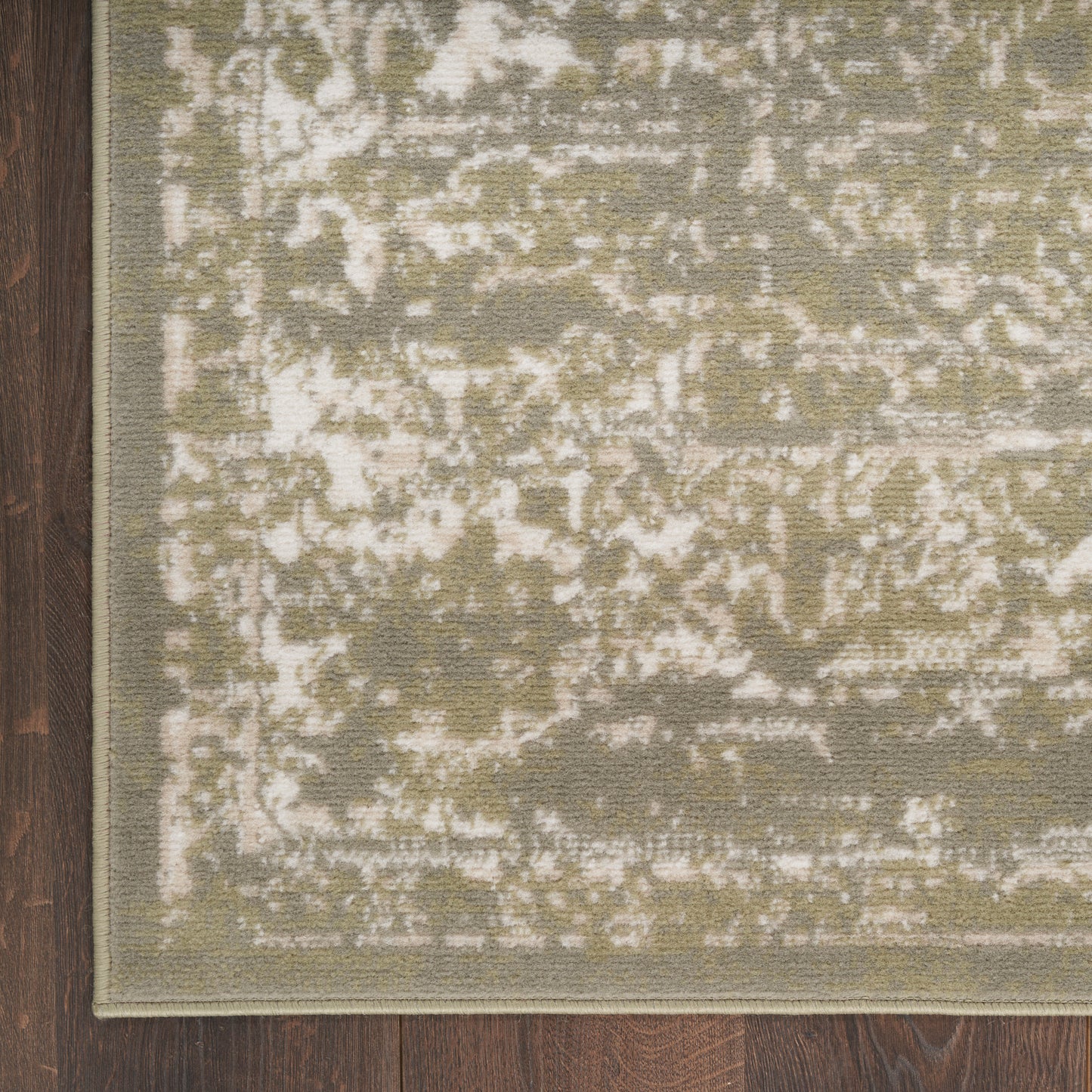 Rectangular olive-green distressed rug with ivory patches and a light beige border on dark wood floor.