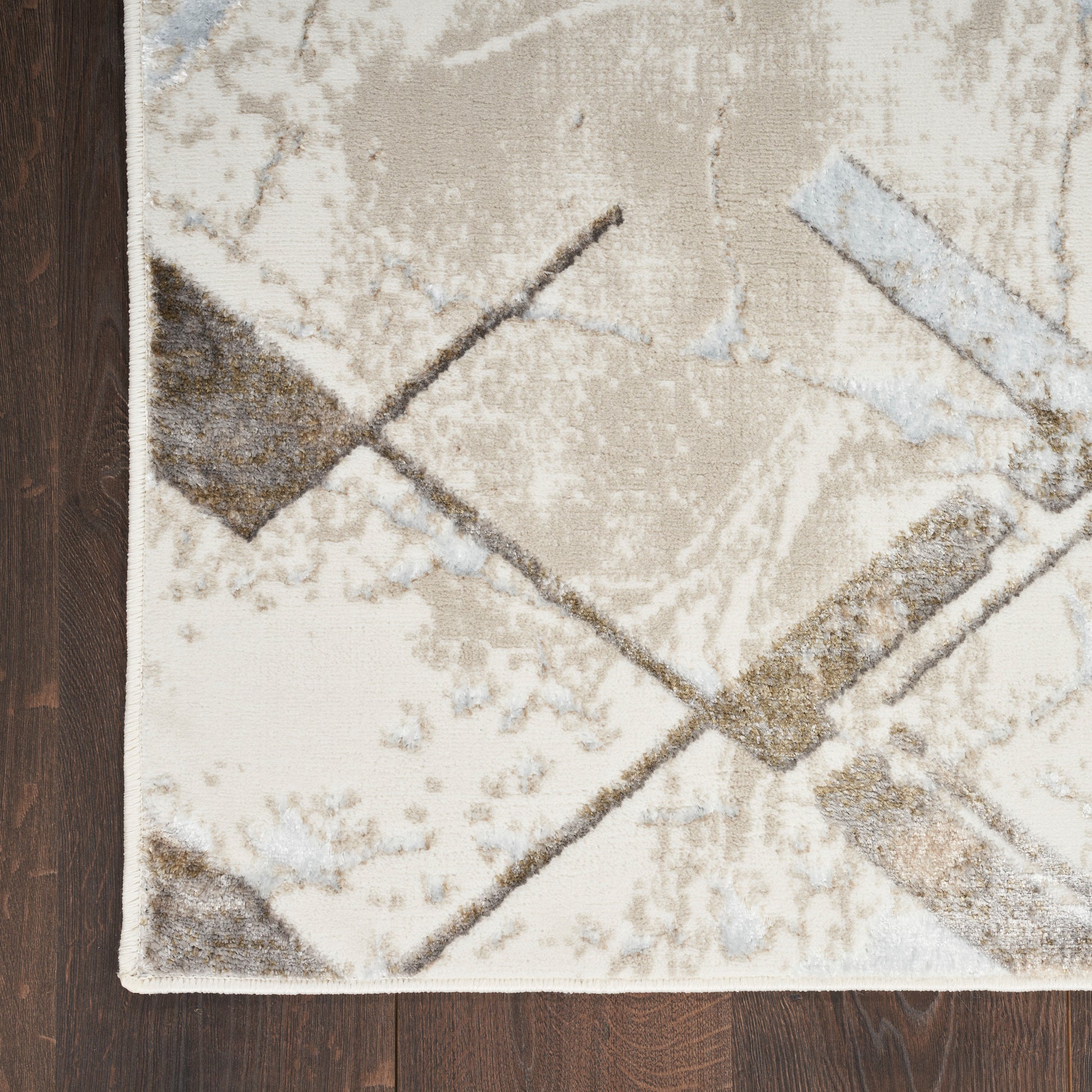 Cream and taupe geometric area rug with gray and light-blue lines on dark wood floor.