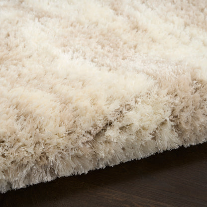 Cream shag rug with long plush fibers and ivory tones resting on dark wood floor.