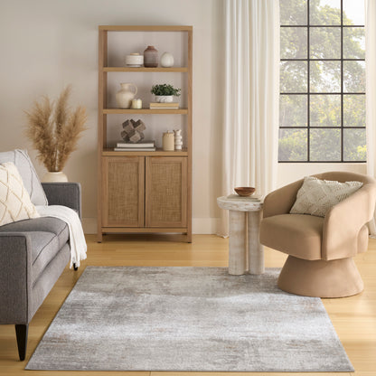Bright living room with a tall wooden shelf, woven cabinet doors, grey sofa, beige curved chair, and a round stone table.
