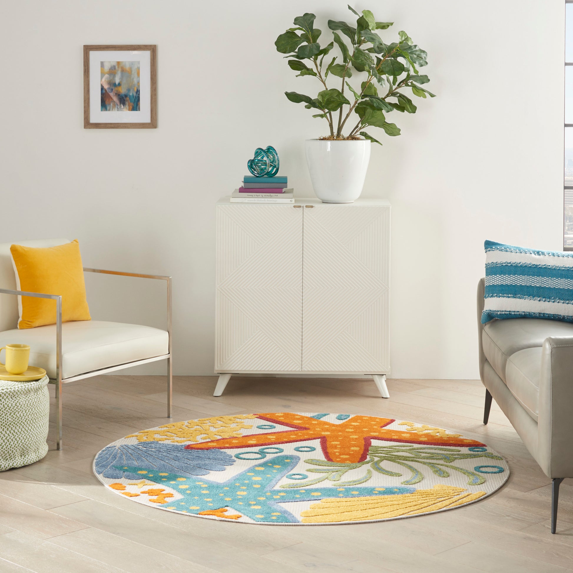 Round colorful area rug with teal, orange and yellow patterns in a bright living room beside a white cabinet and plant.