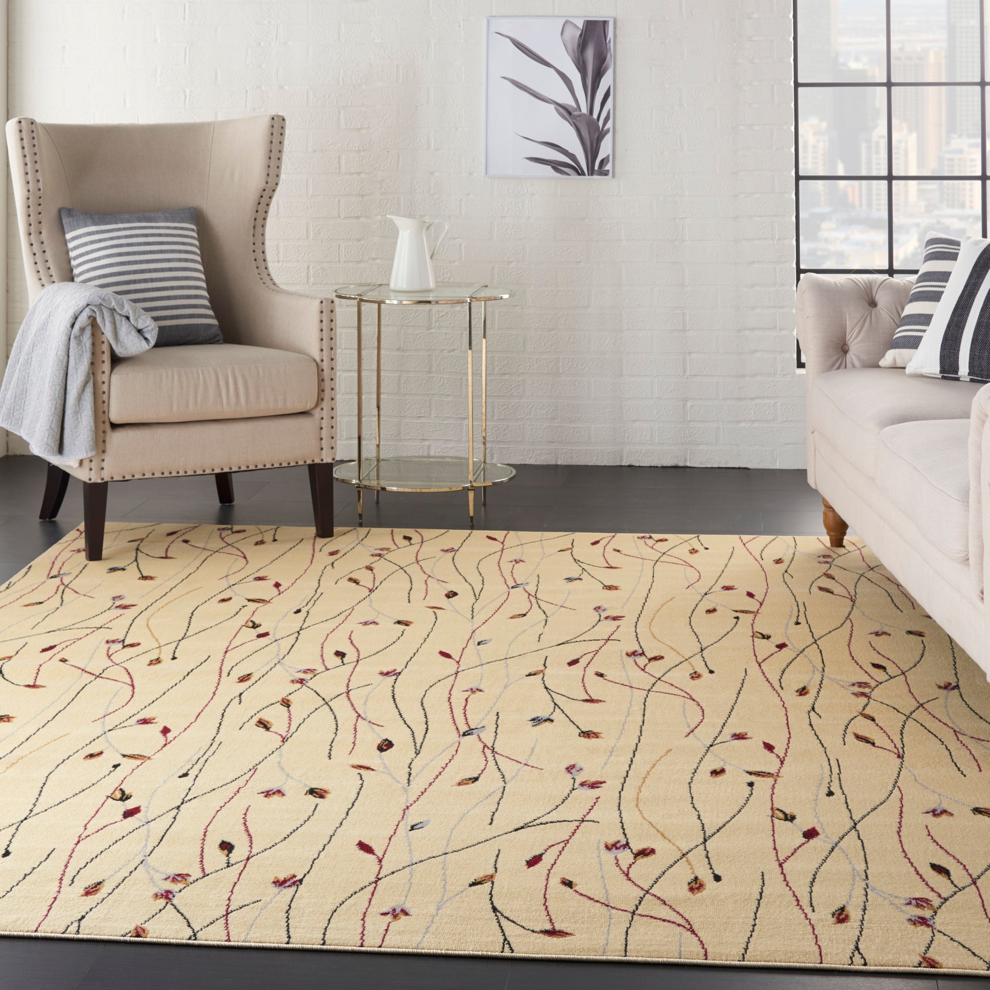 Cream rug with red vines; beige wingback chair with nailhead trim, light sofa with striped cushions & a round glass side table visible around the rug.