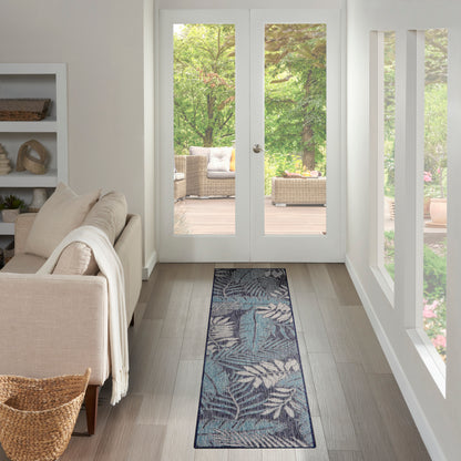 Teal botanical runner rug in a light wood hallway toward white-framed French doors, with beige sofa and wicker basket.