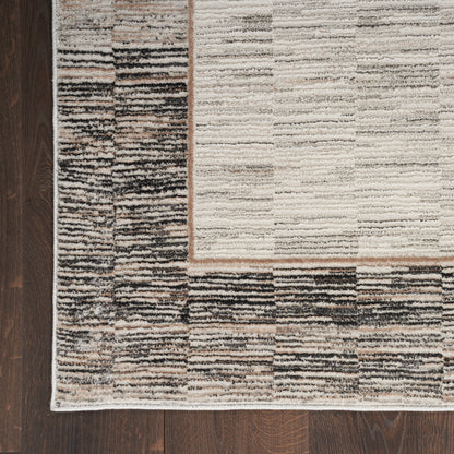 Neutral beige and cream area rug with a dark brown border on dark hardwood floor.