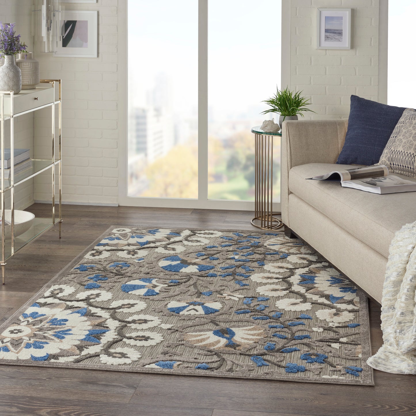 Rectangular area rug with blue, beige and gray floral damask pattern in a modern living room beside a beige sofa.