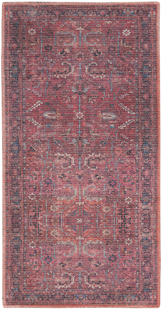Red vintage-style oriental rug with blue & ivory geometric motifs, bordered by a patterned edge & pink fringe.