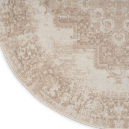 Beige round rug with distressed antique pattern in taupe, plush woven texture and light border.