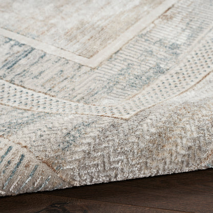 Neutral-toned area rug with a distressed geometric pattern in beige, cream and grey on dark wood floor.
